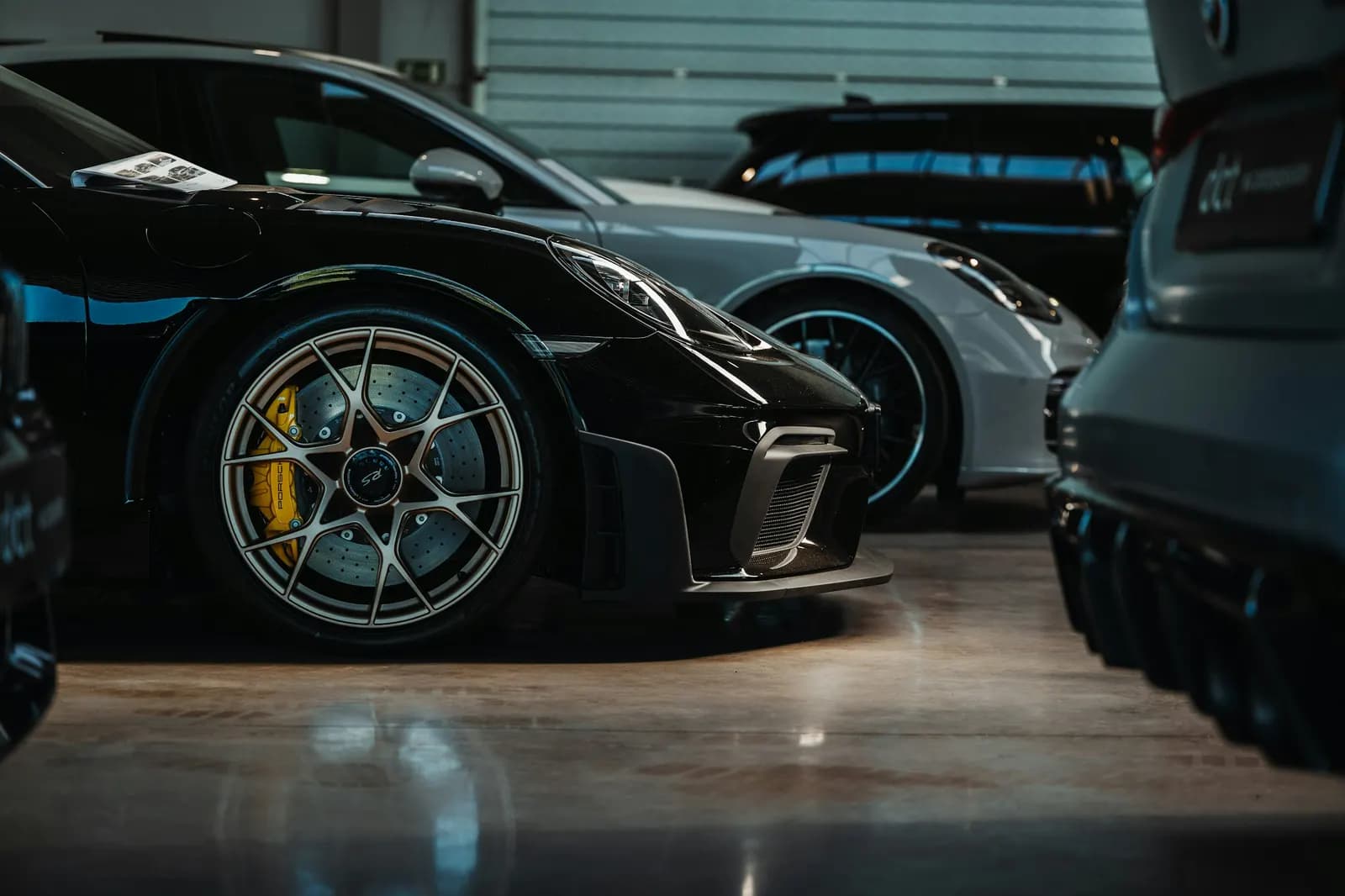 Porsche sports cars on display in a dimly lit luxury showroom