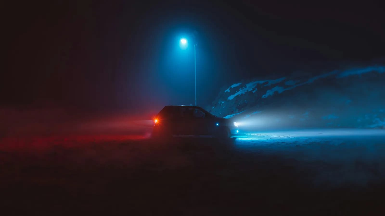 Car headlights cutting through fog on a dark road at night