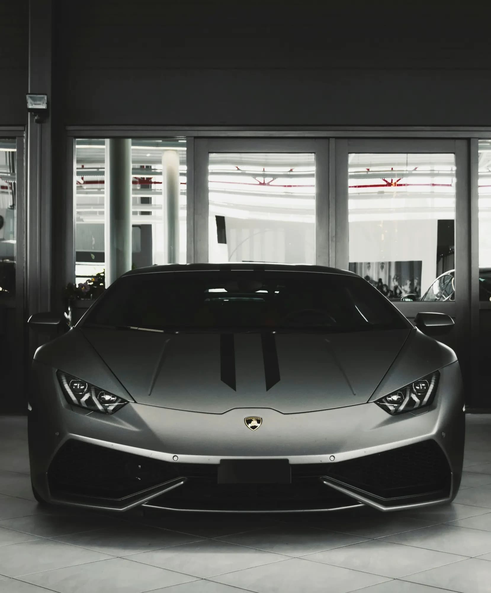 Grey Lamborghini Huracán in a dark showroom, front view