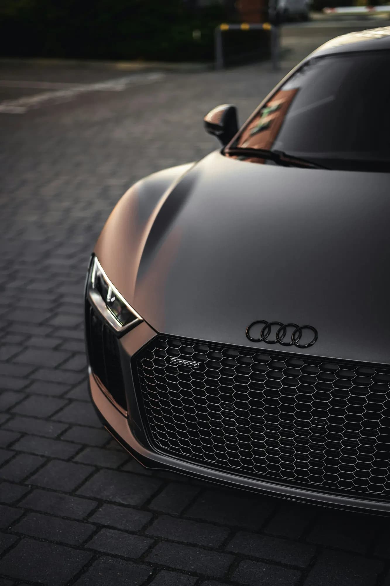 Matte grey Audi R8, front close-up on dark paving