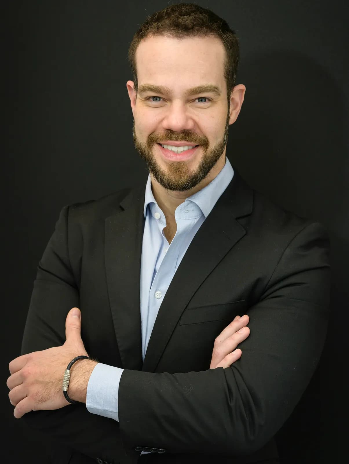 Portrait of a smiling businessman in a dark suit with arms crossed