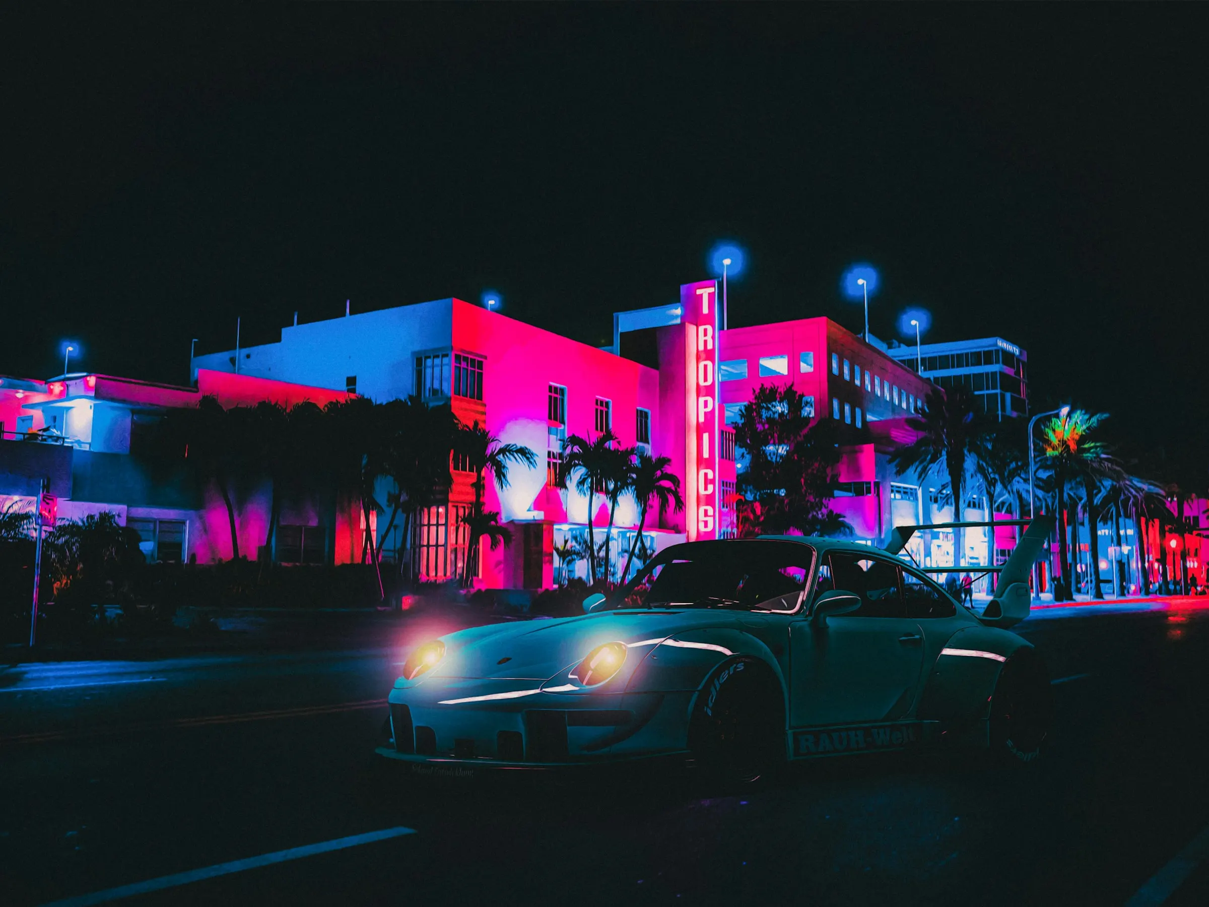 Sports car in front of neon-lit Art Deco hotels on Ocean Drive, Miami Beach, at night