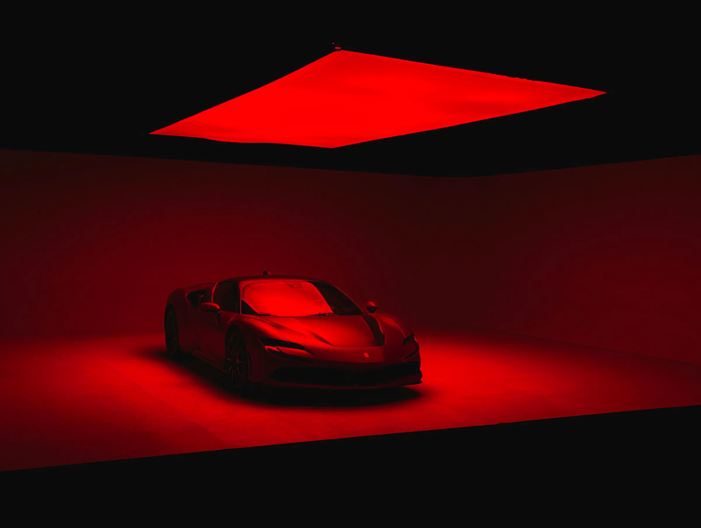 Red Ferrari under dramatic red lighting in a dark studio